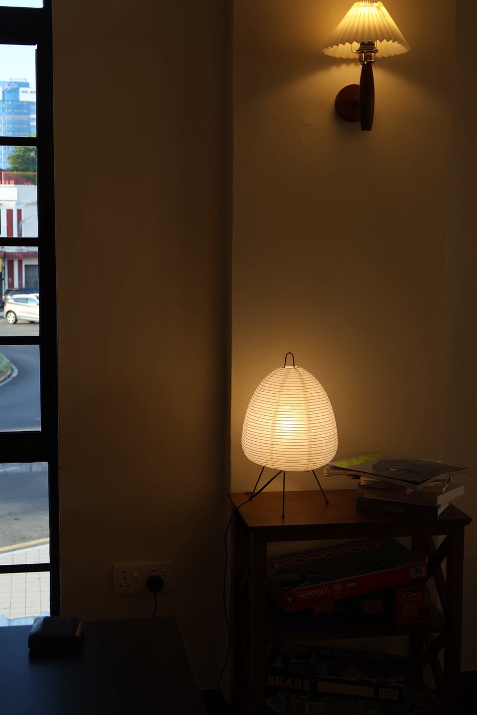 Warm lamplit corner at Autumn café, with a paper lantern lamp on a side table and a window looking out over Miri old town